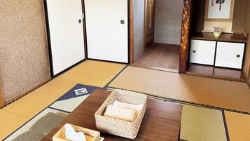 A traditional Japanese room with tatami flooring, a low wooden table, and a woven basket with a towel.