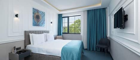 A hotel room with a bed, a desk, a chair, a TV, and a window with curtains.