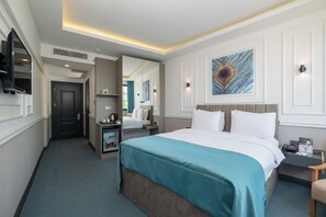 A hotel room with a bed, bedside tables, a mirror, a television, and a painting on the wall. - May Hotel Bosphorus (Istanbul)