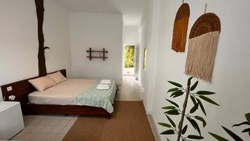 Habitación de hotel con cama, mesita de noche y vista al pasillo.