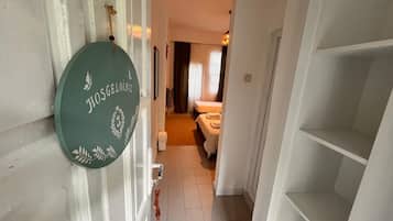 Un pasillo que conduce a un dormitorio con una cama, una mesita de noche y una pequeña mesa.