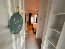 En hall som leder till ett sovrum med en säng, ett nattduksbord och ett litet bord.