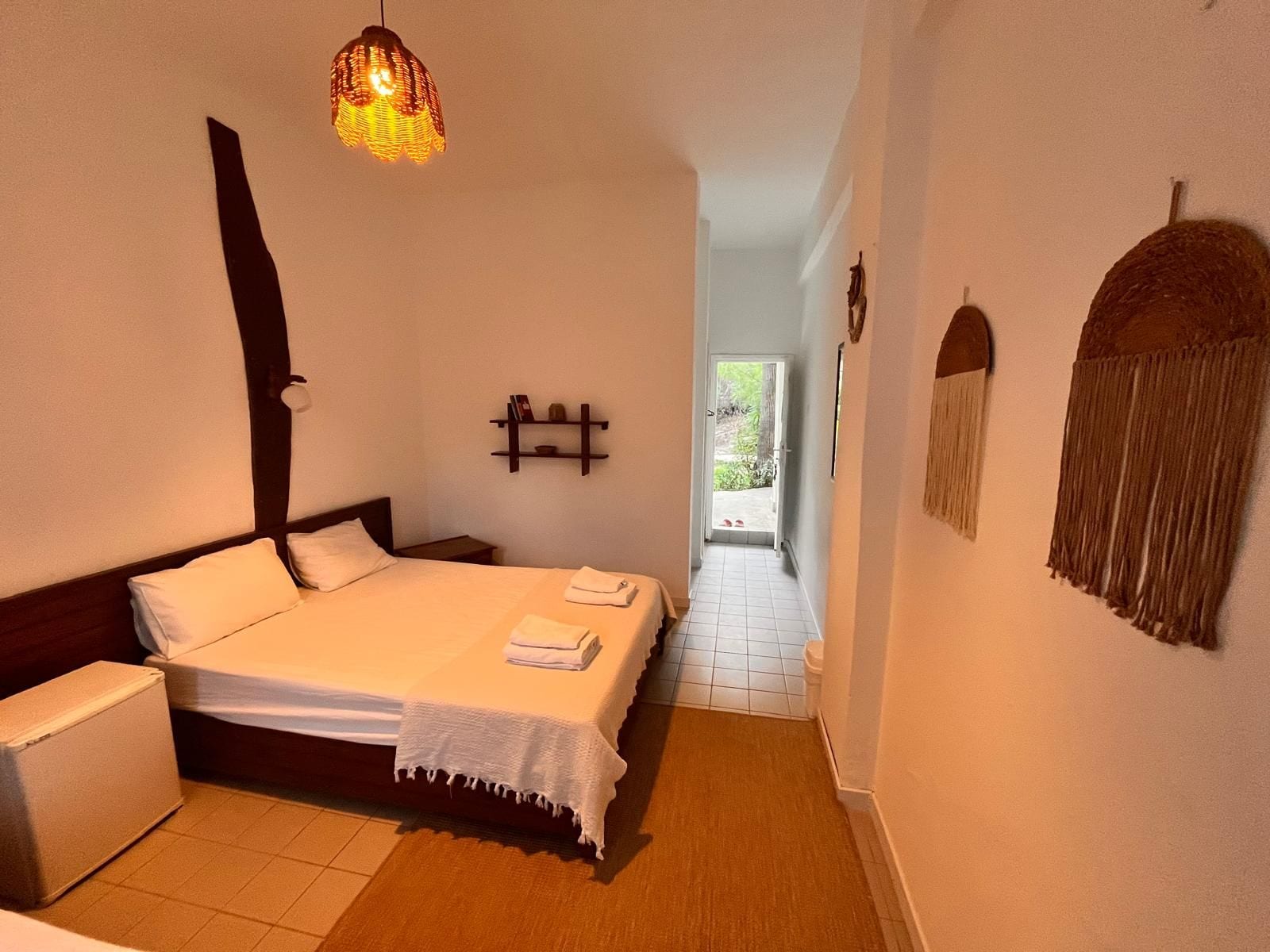 A bedroom with a bed, bedside table, and a hanging light fixture.