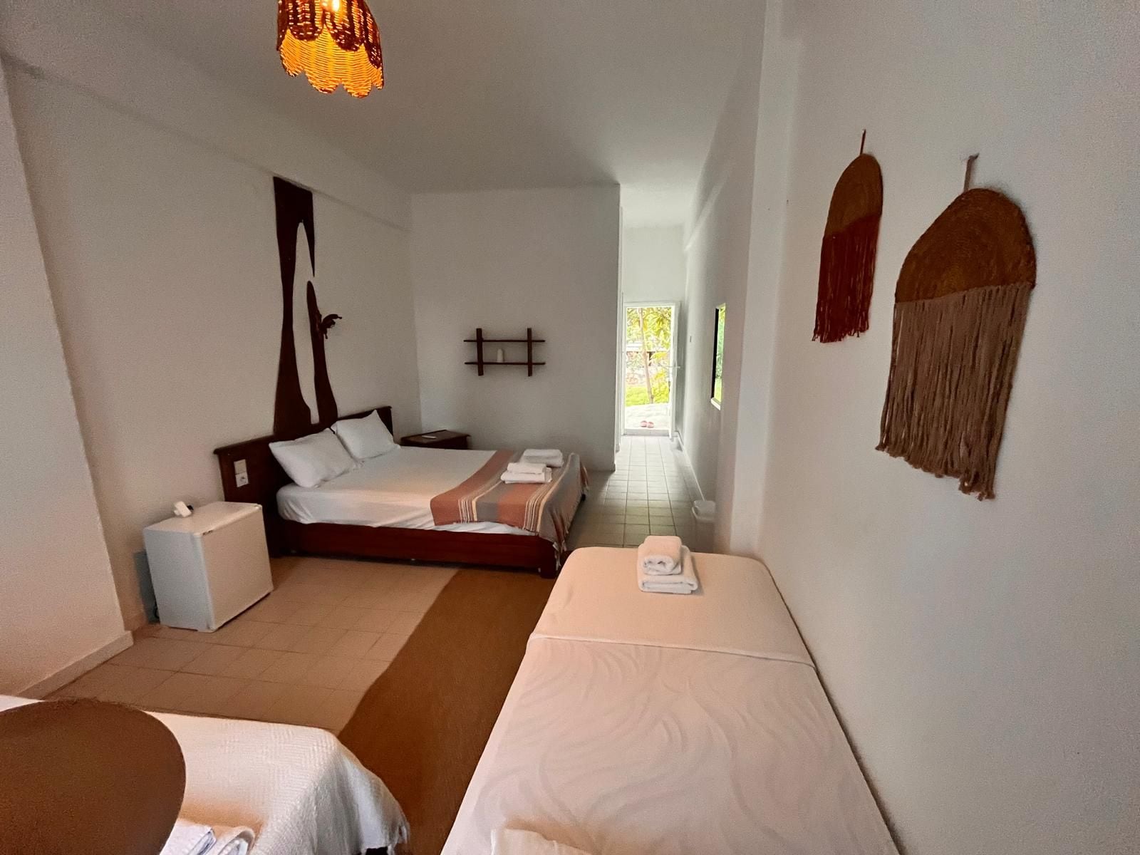 Una habitación de hotel con una cama, una mesita de noche, una silla, una pequeña mesa y un estante en la pared.
