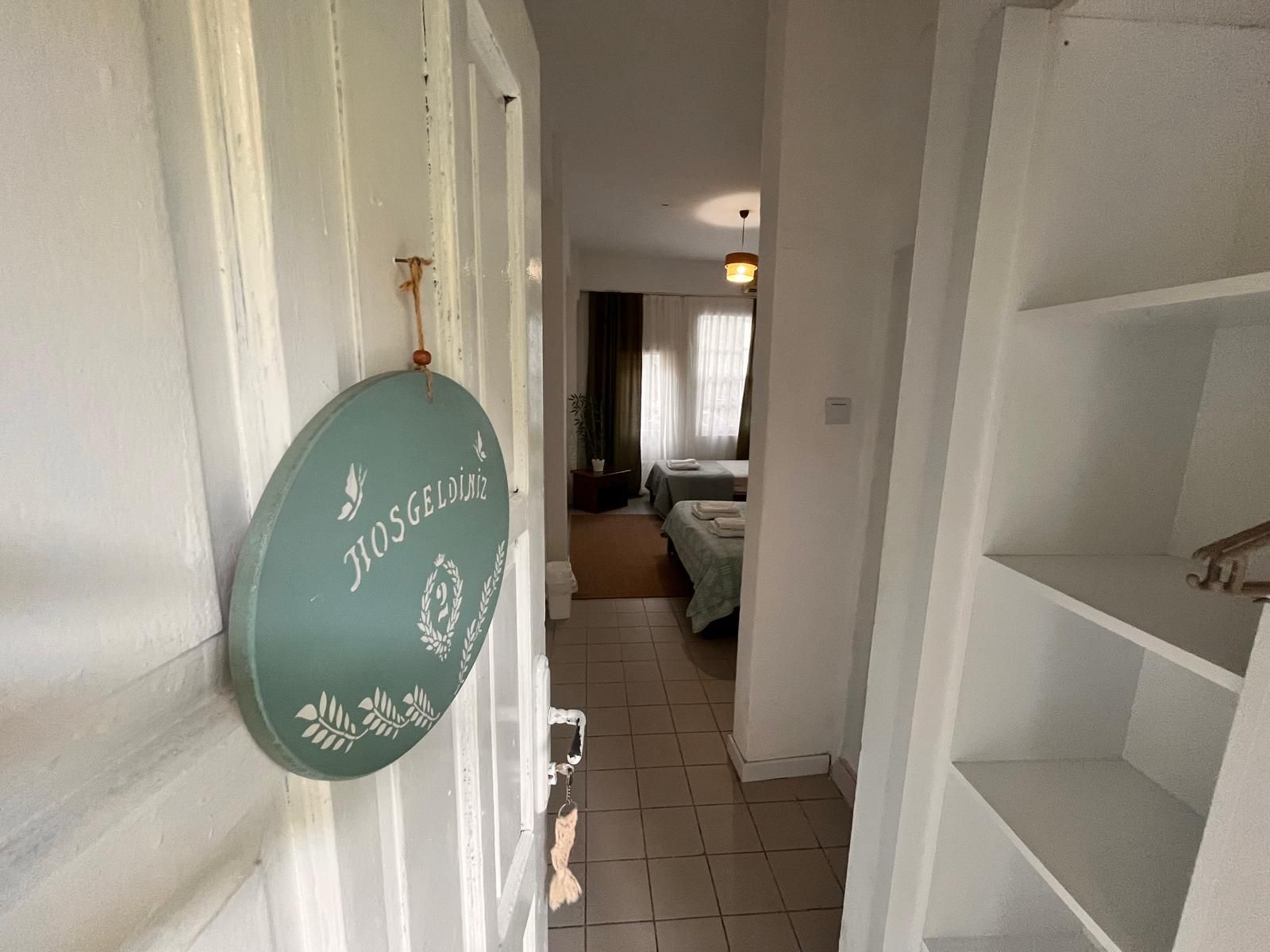 A hallway leading to a room with a bed and a window with curtains.