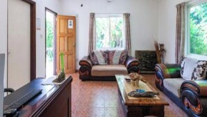 A living room with a sofa, a coffee table, and a television. There is a door leading to another room. - Sibert Residence (La Digue)