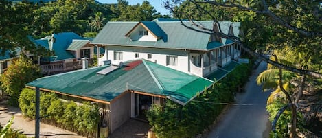 A two-story house with a green roof, a covered porch, and a pathway leading to the entrance.