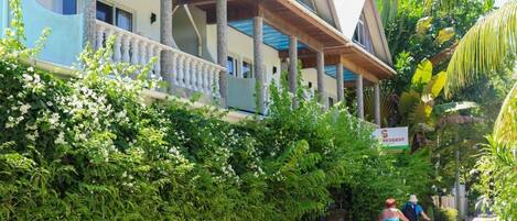 A hotel with a balcony, lush greenery, and a sign indicating it is a resident hotel.
