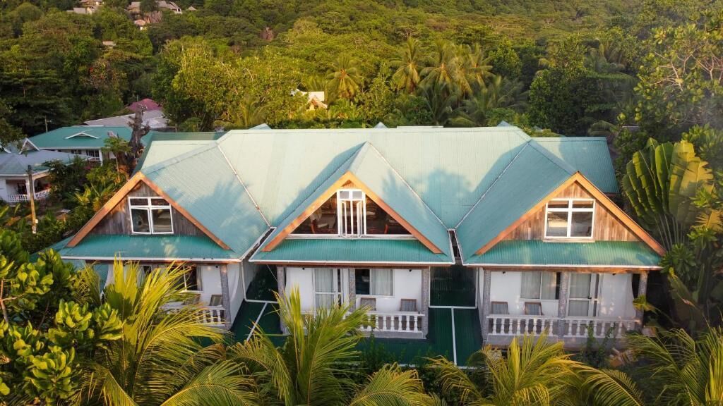 Un immeuble de trois étages surmonté d’un toit végétalisé, entouré d’une végétation luxuriante.