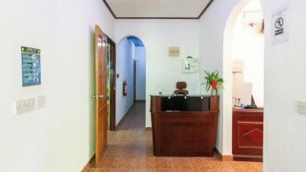 A hallway with a reception desk, a fire extinguisher, and a sign on the wall. - Sibert Residence (La Digue)