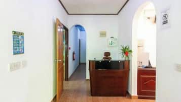 A hallway with a reception desk, a fire extinguisher, and a sign on the wall.