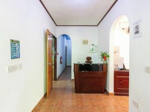 A hallway with a reception desk, a fire extinguisher, and a sign on the wall. - Sibert Residence (La Digue)