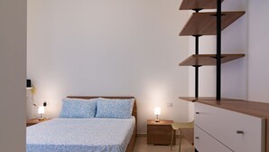 Ein Schlafzimmer mit einem Bett, Nachttischen, einem Schminktisch und einem Sessel.