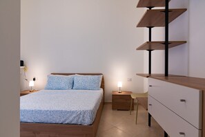 Ein Schlafzimmer mit einem Bett, Nachttischen, einem Schminktisch und einem Sessel.