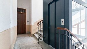 Ein Flur mit Marmorboden, einer Holztür, einer schwarzen Wand und einem Metallgeländer.