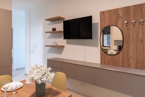A modern dining area with a wooden table, chairs, a vase of flowers, a flat-screen TV mounted on the wall, and a round mirror. - A welcoming and bright 85 square meters apartment, perfect for six people, located on the third floor of a period building with an elevator (NOT accessible to people with disabilities).The property enjoys an excellent location in Palermo (within the limi (Palermo)