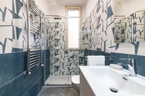 Een moderne badkamer met een douche, toilet en een groot bad.