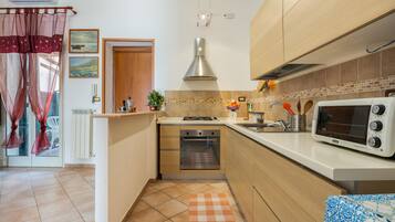 Een functionele keuken met een inbouwoven, een magnetron en een gasfornuis.