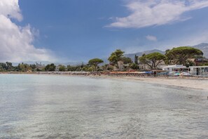 A beach with clear water, umbrellas, and buildings in the background. - Apartment 'Mondello Holidays - Casa Neruda' with Sea View, Wi-Fi and Air Conditioning (Palermo)
