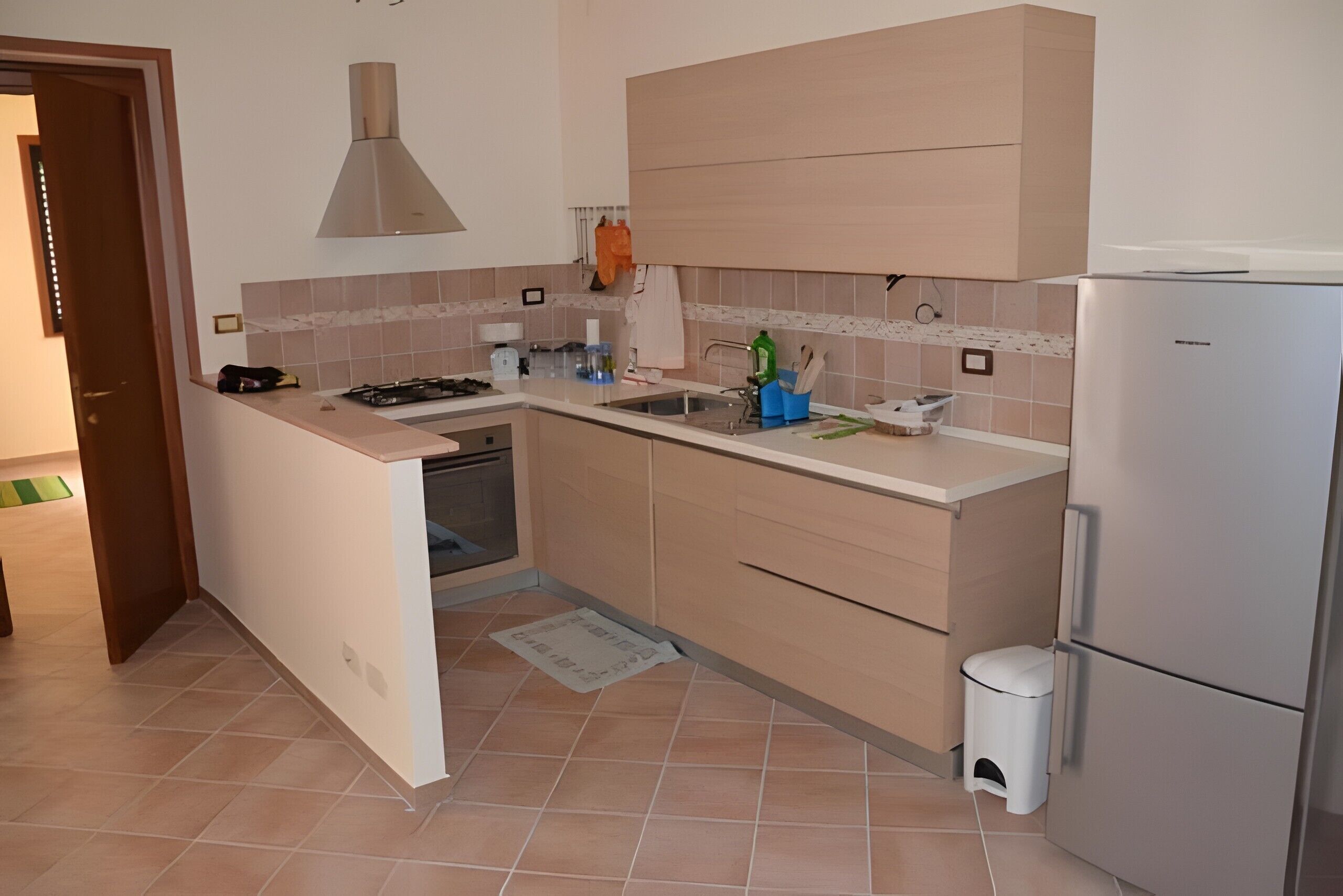 Una cocina compacta con horno integrado, un fregadero y un refrigerador.