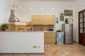 A modern kitchen with a central island, a built-in oven, a microwave, and a refrigerator. - Apartment 'Mondello Holidays - Casa Neruda' with Sea View, Wi-Fi and Air Conditioning (Palermo)