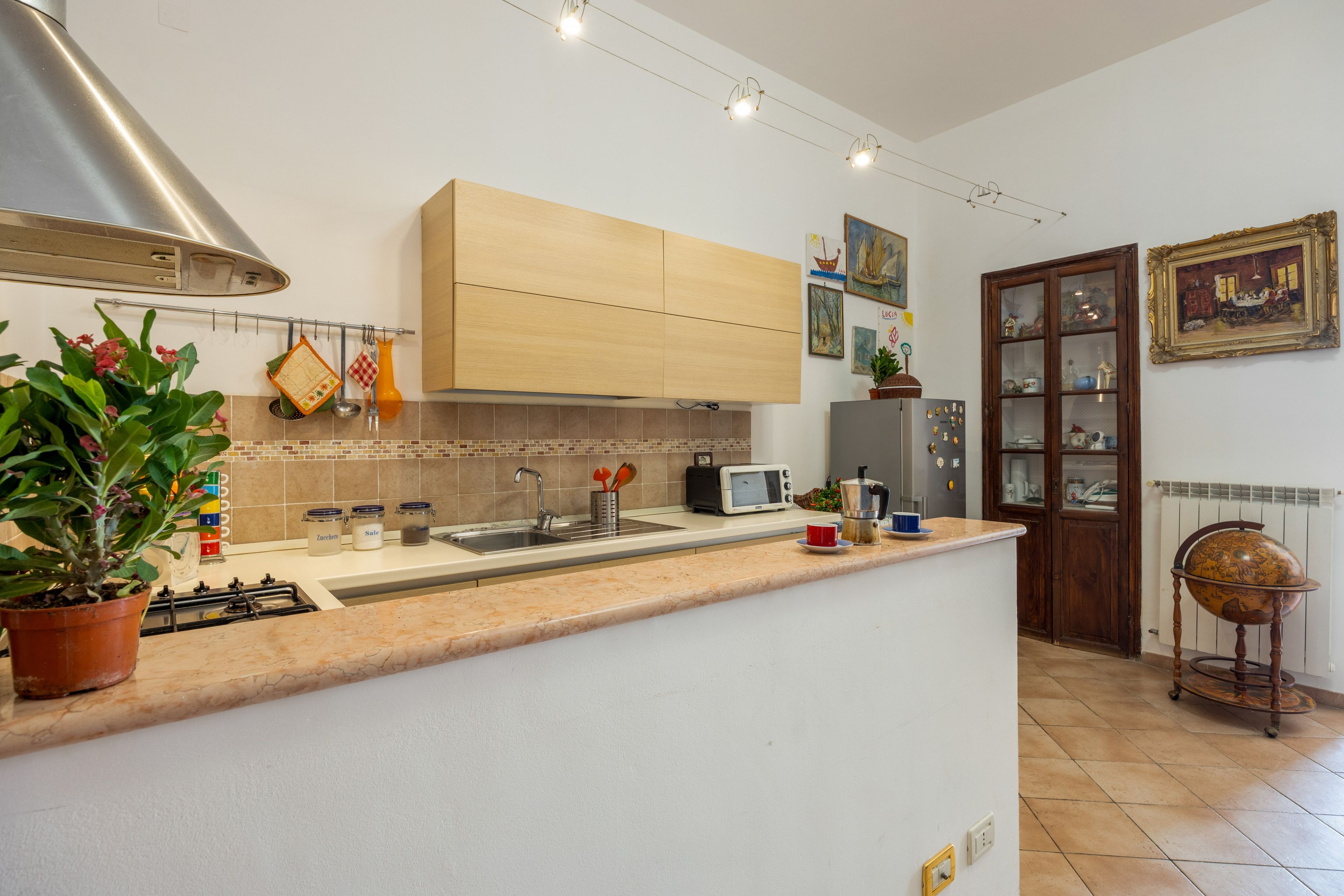 Une cuisine dotée d’un îlot central, d’une cuisinière, d’un évier et d’un four à micro-ondes. On y trouve des placards au-dessus du plan de travail et une fenêtre avec des rideaux.