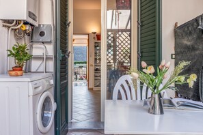 Una cocina funcional con lavadora, una planta en maceta y una zona de comedor con mesa y sillas.