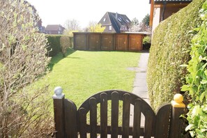 A residential property with a well-maintained lawn, a wooden gate, and a brick building in the background. - Modern beachfront apartment with exceptional sea views at Schönberger Strand (Schönberg (Holstein))