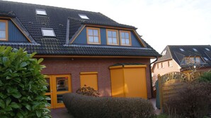 Een woonhuis met een schuin dak, dakramen en een garage met gele luiken.