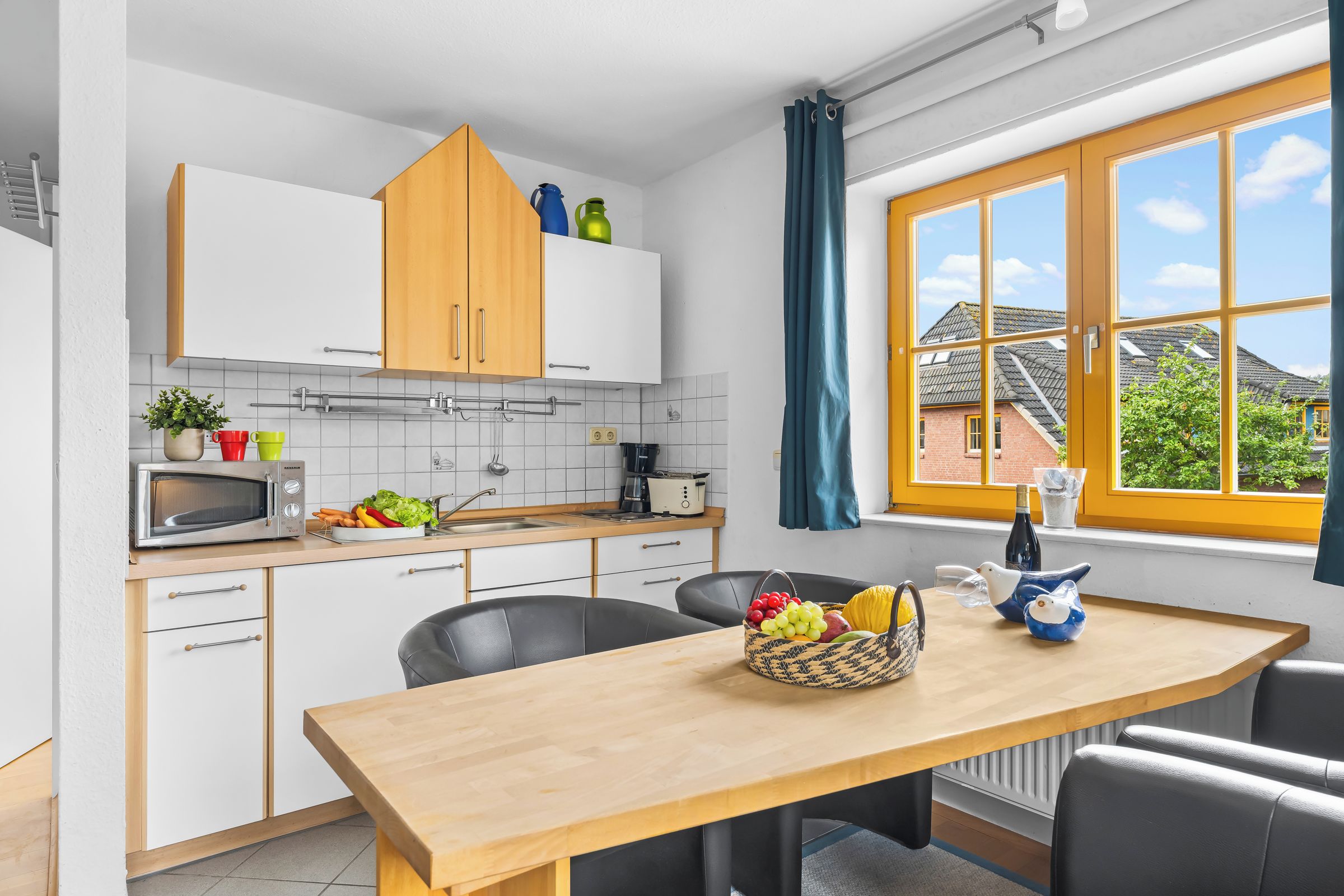 A modern kitchen with white cabinets, a wooden countertop, and a dining table with chairs.