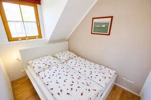 A bedroom with a bed, a window, a picture on the wall, and a lamp. - Modern beachfront apartment with exceptional sea views at Schönberger Strand (Schönberg (Holstein))