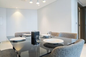 A modern dining area with a glass table, four chairs, and a black center console. - StayShort - Studio in Business Bay Balcony that Sleeps 2 (Business Bay)