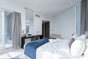 A modern hotel room with a large bed, a desk, a mirror, and a view of the city. - StayShort - Studio in Business Bay Balcony that Sleeps 2 (Business Bay)