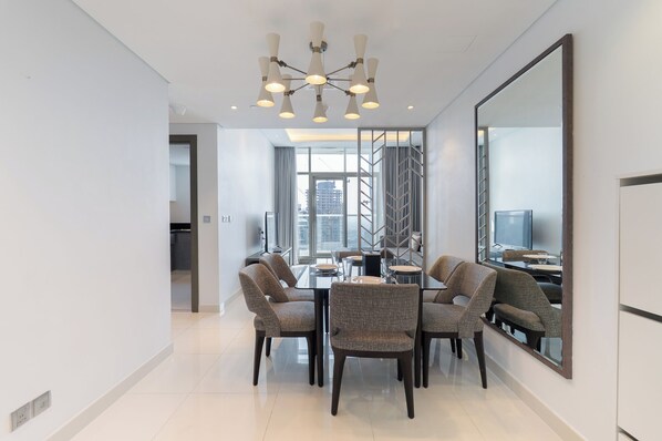 A modern dining area with a glass table, dark chairs, and a large mirror. - StayShort - Studio in Business Bay Balcony that Sleeps 2 (Business Bay)