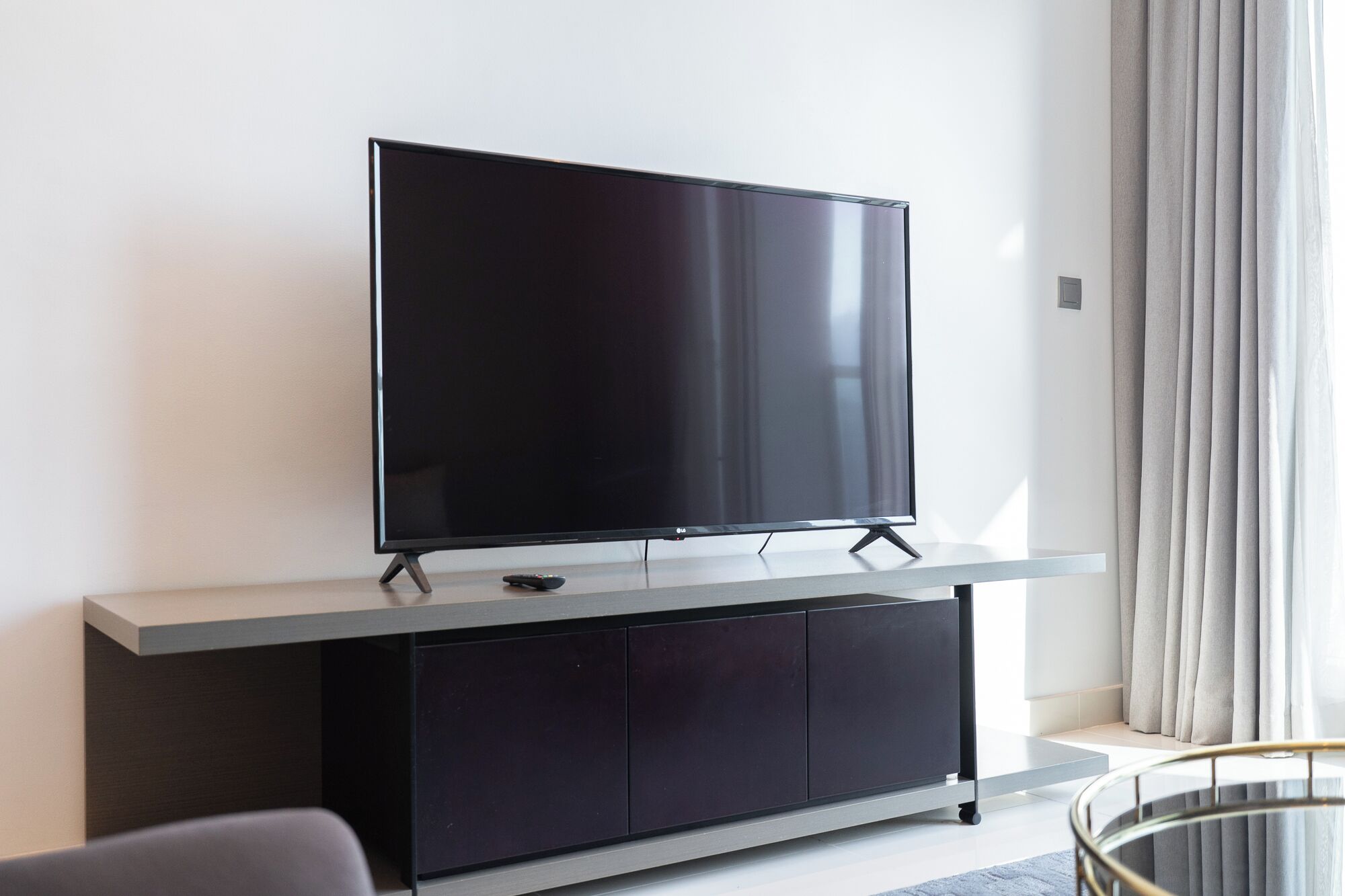 A flat-screen TV on a stand in a modern room with a minimalist design.