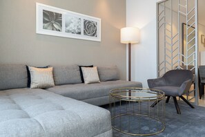 A modern living room with a sectional sofa, a round coffee table, and a grey armchair. - StayShort - Studio in Business Bay Balcony that Sleeps 2 (Business Bay)