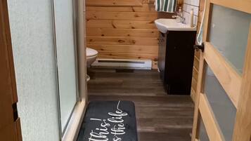 A narrow hallway leading to a bathroom with a toilet, sink, and a window.