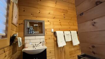A wooden-paneled bathroom with a sink, mirror, and towels.