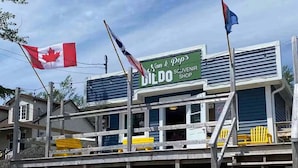 Un edifici de dues plantes amb un cartell de 'Van & Pop's Souvenir Shop' i banderes del Canadà.