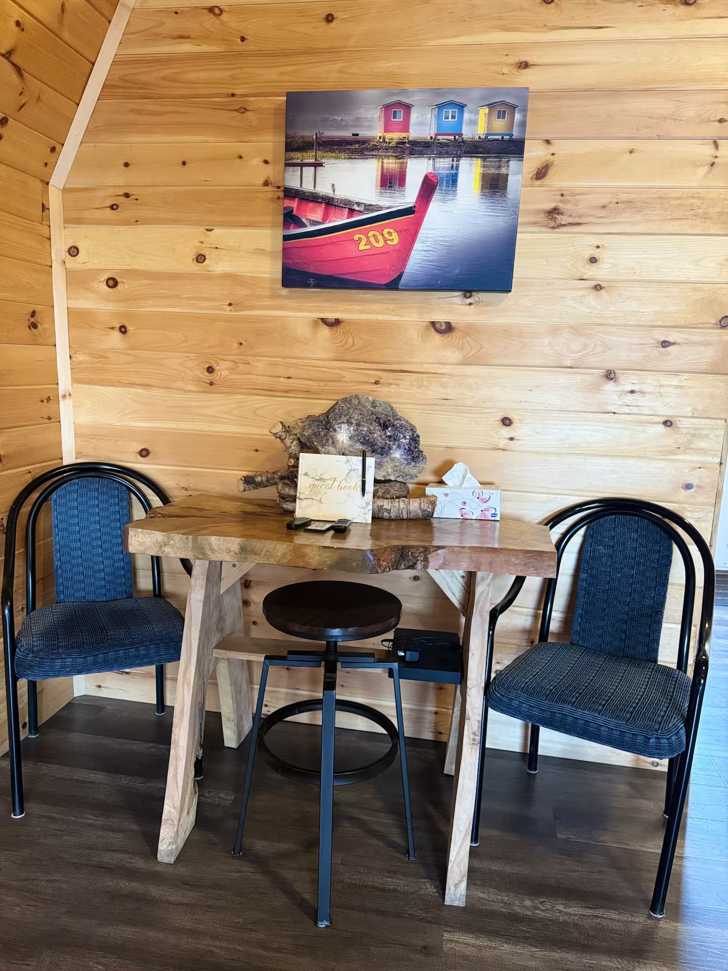 Een houten interieur met een tafel, twee stoelen, een schilderij en een rots als decoratie.