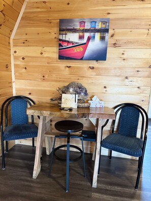 A wooden interior with a table, two chairs, a painting, and a rock centerpiece.