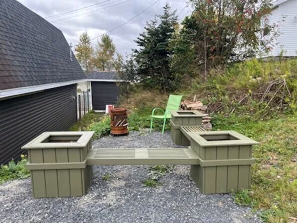A gravel area with two green planters and a green chair.