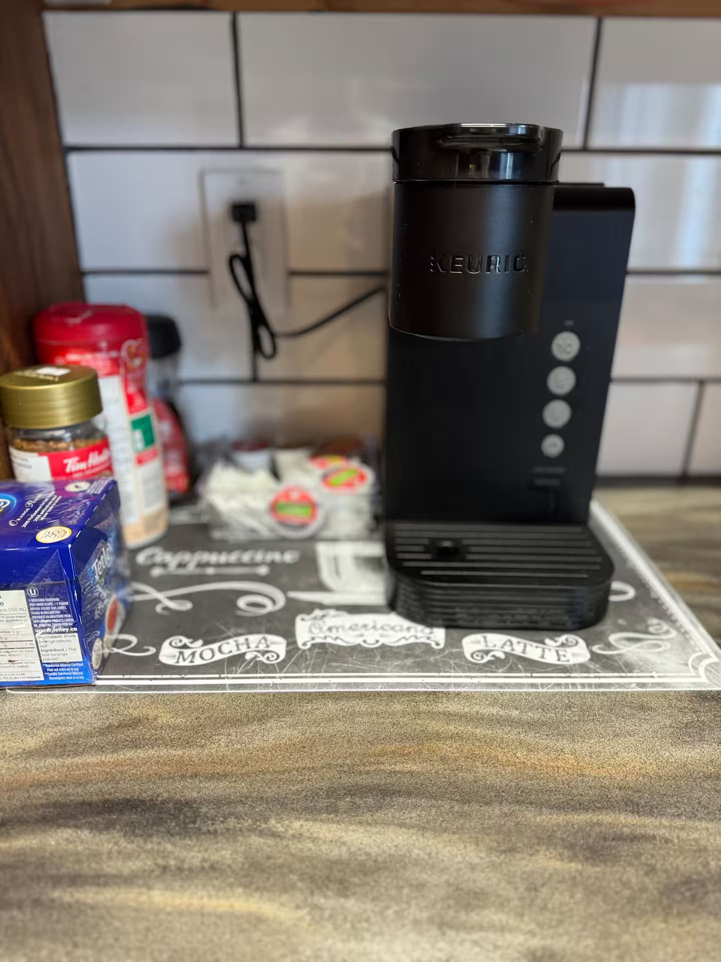 Una encimera de cocina con una cafetera, un dispensador de cápsulas de café y un molinillo.