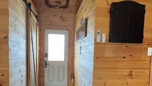 A wooden interior with a ceiling fan, a door at the end of a hallway, and a deer head mounted on the wall.