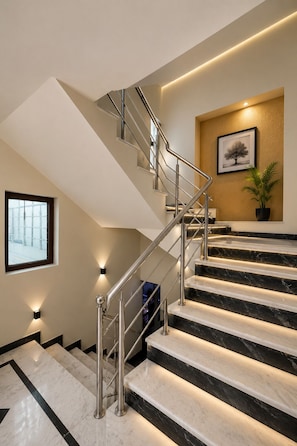 A modern staircase with a metal railing, marble steps, and wall-mounted lighting. - Hotel Max Apple In (Agra)