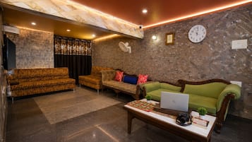 Una sala de estar moderna con una pared de piedra, un sofá verde, un sofá estampado con diseño de tigre y una mesa de centro con una computadora portátil.