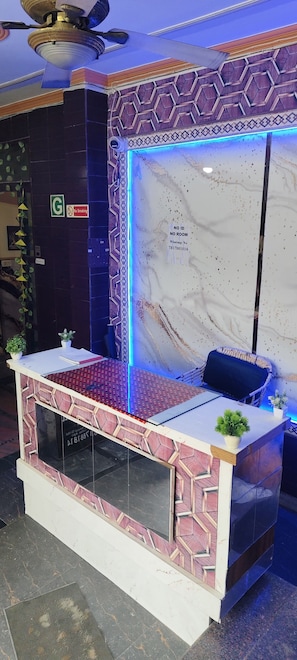 A reception desk with a marble back wall, a no smoking sign, and a phone. - Hotel Max Apple In (Agra)