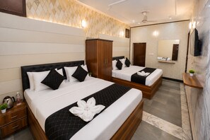 Habitación de hotel con dos camas, un armario, un espejo y una planta pequeña.