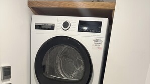 A stacked Bosch washing machine with a self-cleaning function, a control panel, and a digital display. - Welcome to the The Old Manse, Horton, newly refurbished, meticulously designed. (Swansea)