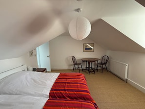 Ein Schlafzimmer mit einem Bett, einem Esstisch mit Stühlen, einem Heizkörper und einer Hängelampe.